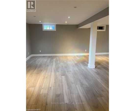 A room with wooden flooring and a grey wall.