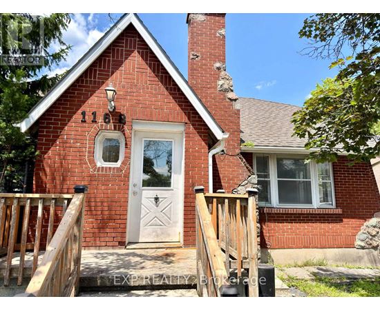 A red brick house with a white door and a window.