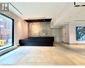 A spacious office lobby with a black reception desk and a large painting on the wall.