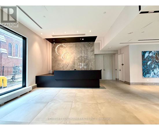 A spacious office lobby with a black reception desk and a large painting on the wall.