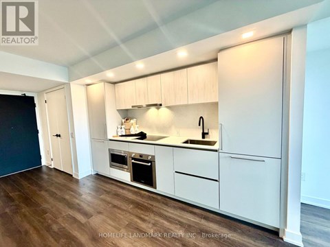 A kitchen with white cabinets and a wooden floor.