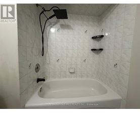 A white bathtub in a bathroom with a shower head above it.