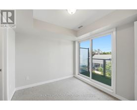 A room with a window showing a view of a house and trees outside.