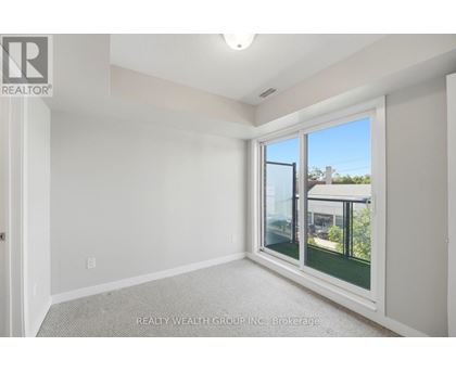 A room with a window showing a view of a house and trees outside.