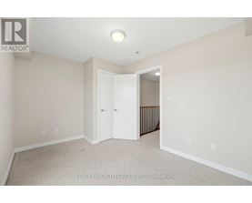A white bedroom with a carpet floor and a doorway leading to a hallway.