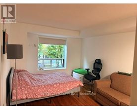 A bedroom with a bed, chair, and window.