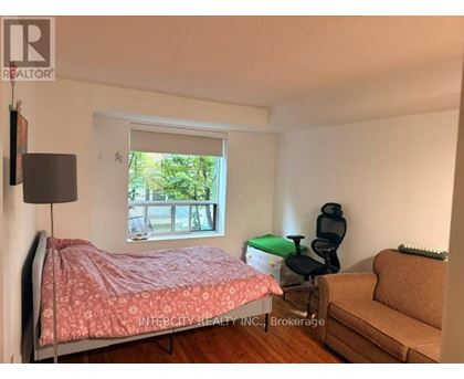 A bedroom with a bed, chair, and window.