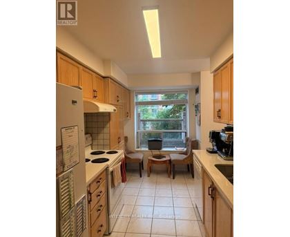 A kitchen with wooden cabinets and a window seat.