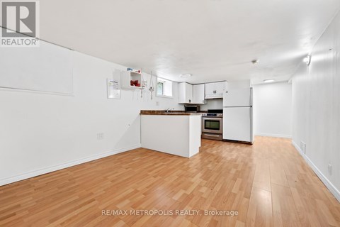 A spacious kitchen with white cabinets and a wooden floor.