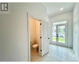 A white bathroom with a toilet and a door leading to a balcony.