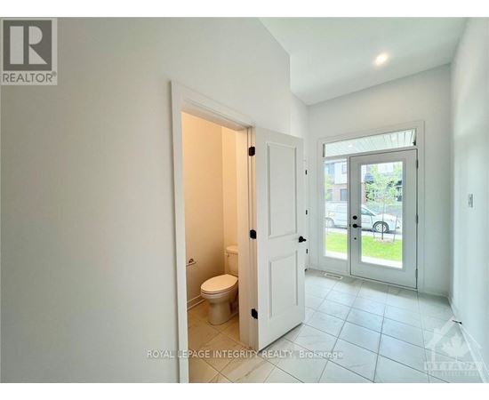 A white bathroom with a toilet and a door leading to a balcony.