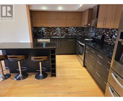 A kitchen with a black counter top and wooden floors.