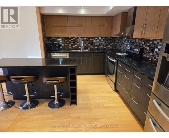 A kitchen with a black counter top and wooden floors.