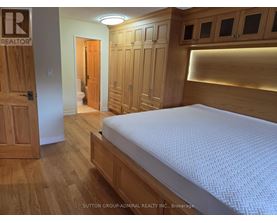 A bedroom with a bed, wooden floors, and a wooden door.