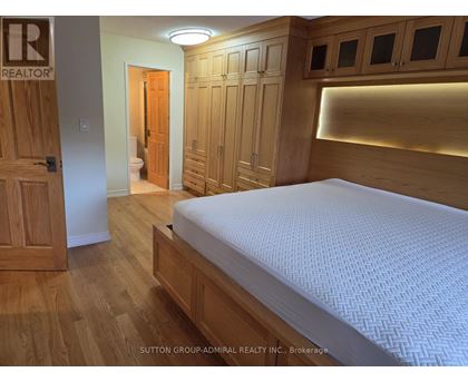 A bedroom with a bed, wooden floors, and a wooden door.
