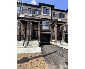 A modern two-story residential building with a black front door and a small front yard.