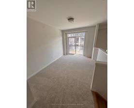 A room with a carpeted floor and a window with a view of a building outside.