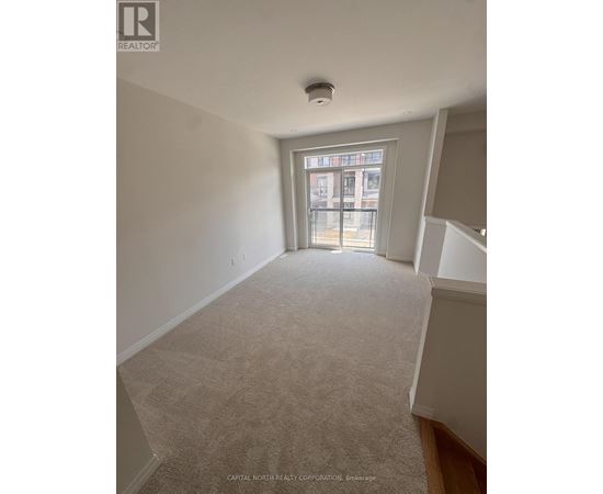 A room with a carpeted floor and a window with a view of a building outside.