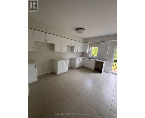 A white kitchen with tile flooring and white cabinets.