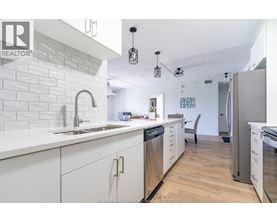 A kitchen with white cabinets and a white brick wall.
