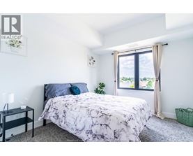 A bedroom with a bed, nightstand, and window.