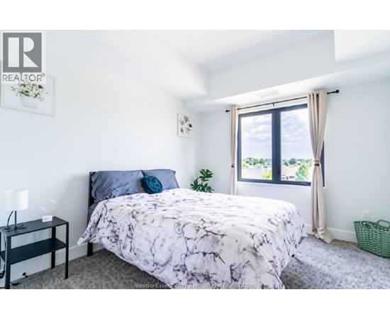 A bedroom with a bed, nightstand, and window.
