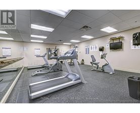 A gym with treadmills, exercise bikes, and a television.