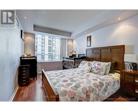 A bedroom with a large bed and a window overlooking a cityscape.