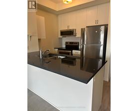 A modern kitchen with a black countertop and stainless steel appliances.