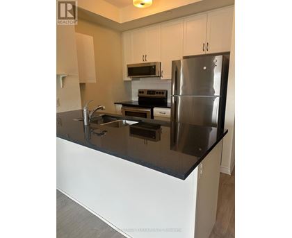 A modern kitchen with a black countertop and stainless steel appliances.
