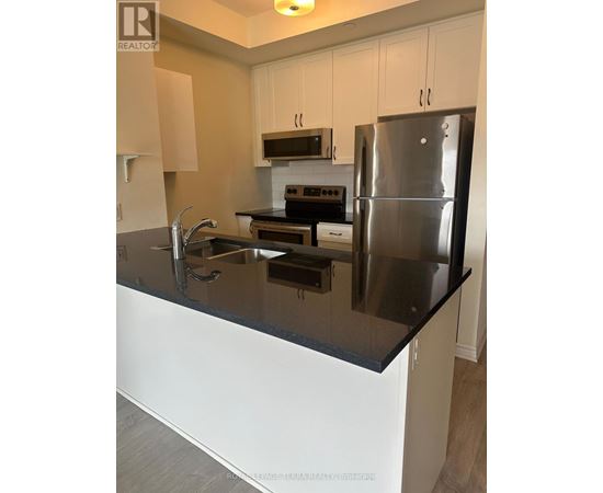 A modern kitchen with a black countertop and stainless steel appliances.