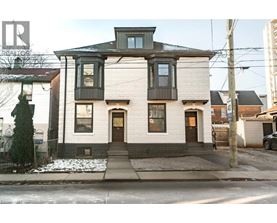 A two-story house with a white facade and a dark brown roof.
