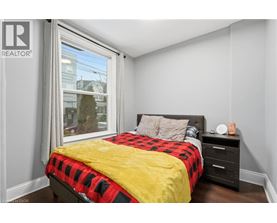 A bedroom with a bed, nightstand, and window.