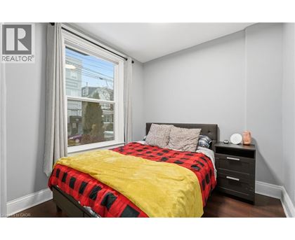 A bedroom with a bed, nightstand, and window.