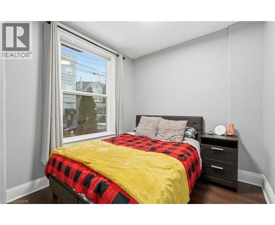 A bedroom with a bed, nightstand, and window.