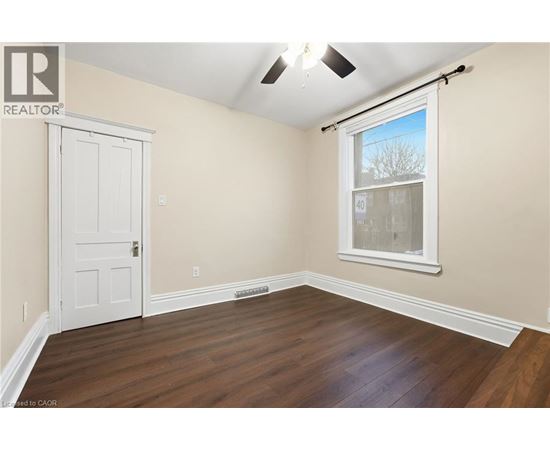A room with a white door and a window with a view of trees outside.
