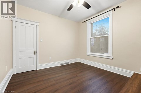 A room with a white door and a window with a view of trees outside.