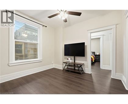 A living room with a flat screen TV and a ceiling fan.
