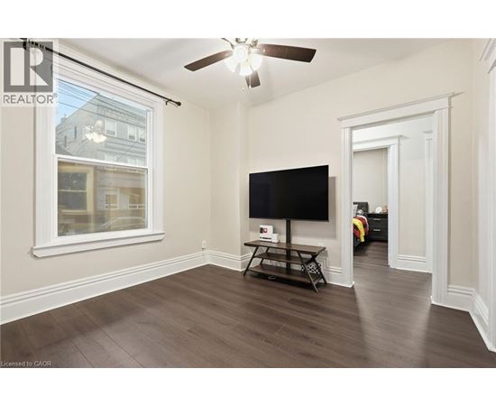 A living room with a flat screen TV and a ceiling fan.