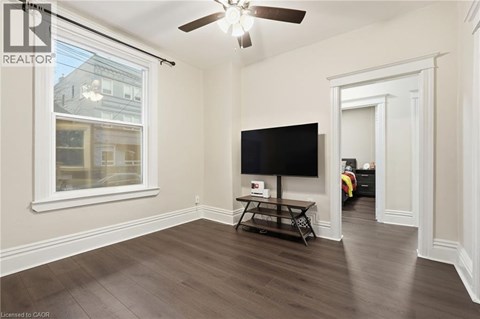 A living room with a flat screen TV and a ceiling fan.