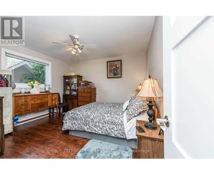 A bedroom with a bed, dresser, and ceiling fan.