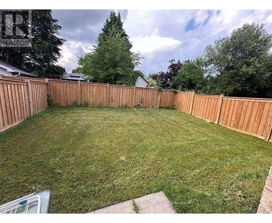 A backyard with a wooden fence and a green lawn.
