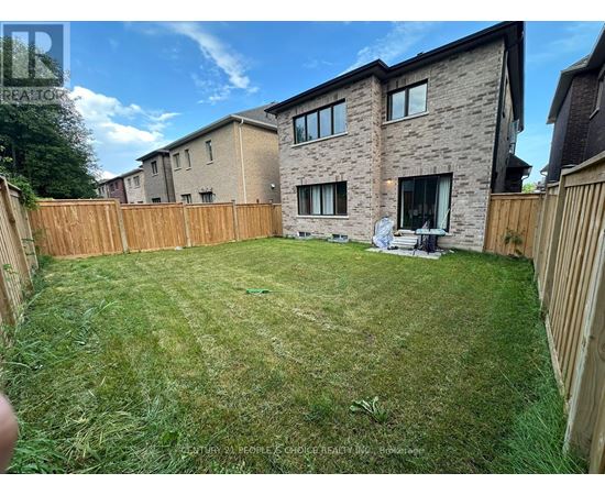 A backyard with a wooden fence and a green lawn.