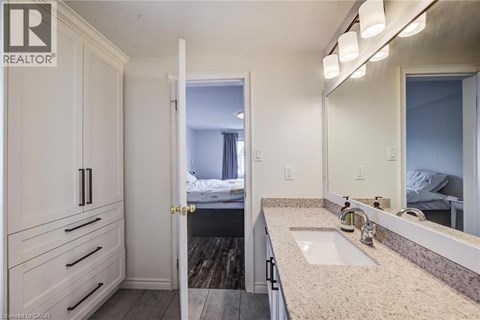 A bathroom with a sink, mirror, and a bedroom in the background.