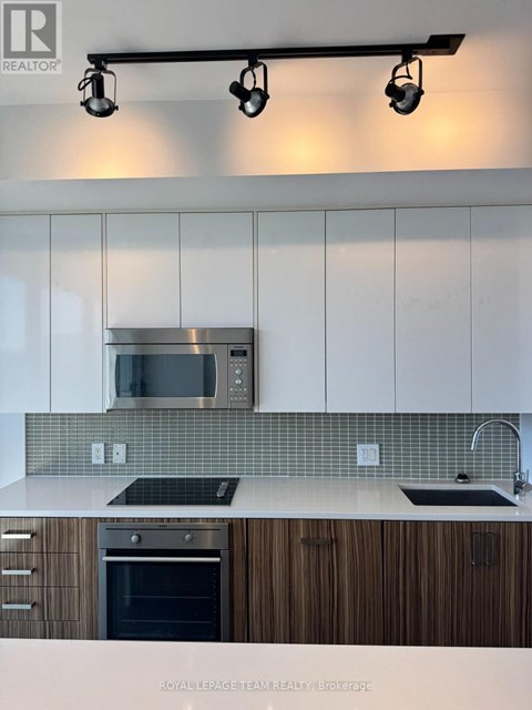 A modern kitchen with white cabinets and a stainless steel microwave above the stove.