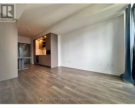 A spacious room with wooden flooring and a large window.