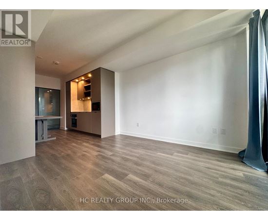 A spacious room with wooden flooring and a large window.