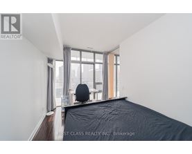 A bedroom with a large bed and a window overlooking a cityscape.