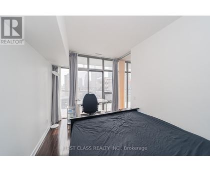A bedroom with a large bed and a window overlooking a cityscape.