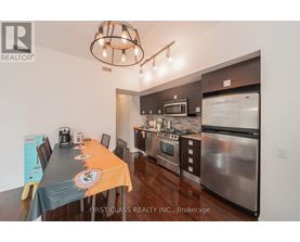 A kitchen with a dining table set up with orange tablecloth and a signboard on the table.